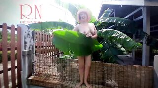 Rural striptease. Country girl dancing in the yard of her house Rustic striptease with banana leaf
