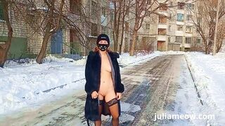 Naked tomboy in a fur coat swings on a swing in winter