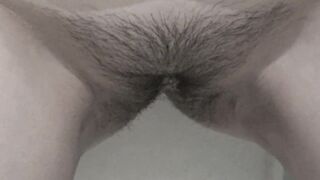 A milf with a hairy pussy pees while standing.